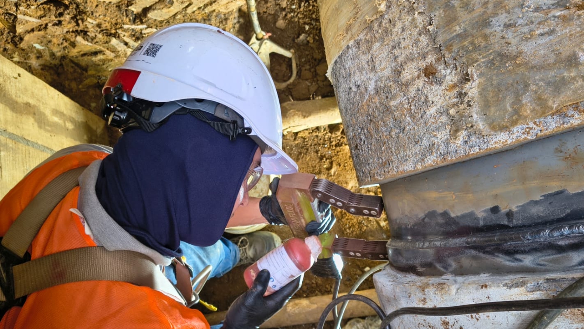 Técnico aplicando partículas magnéticas en la soldadura de una tubería de acueducto