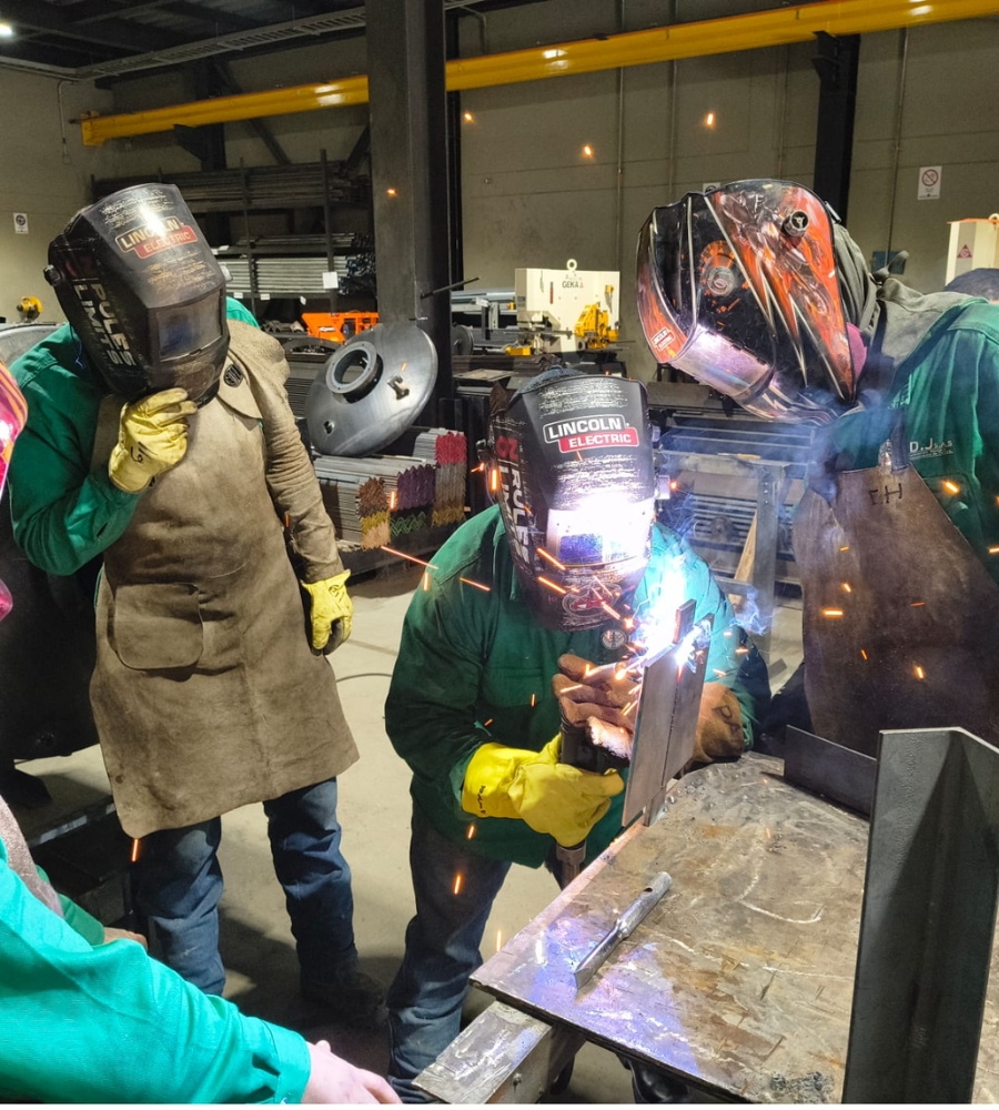 Instructor acompañando a soldadores durante una práctica de soldadura en taller