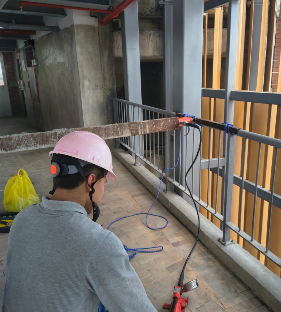 Técnico ejecutando prueba de empuje en el pasamanos de una baranda metálica