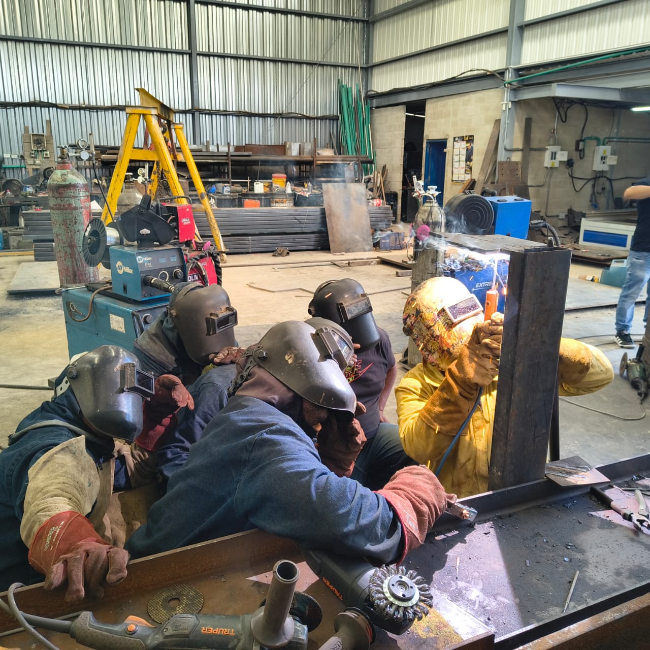 Grupo de soldadores en práctica supervisada de soldadura en taller