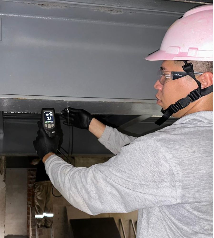 Técnico midiendo el espesor de recubrimiento en una estructura metálica
