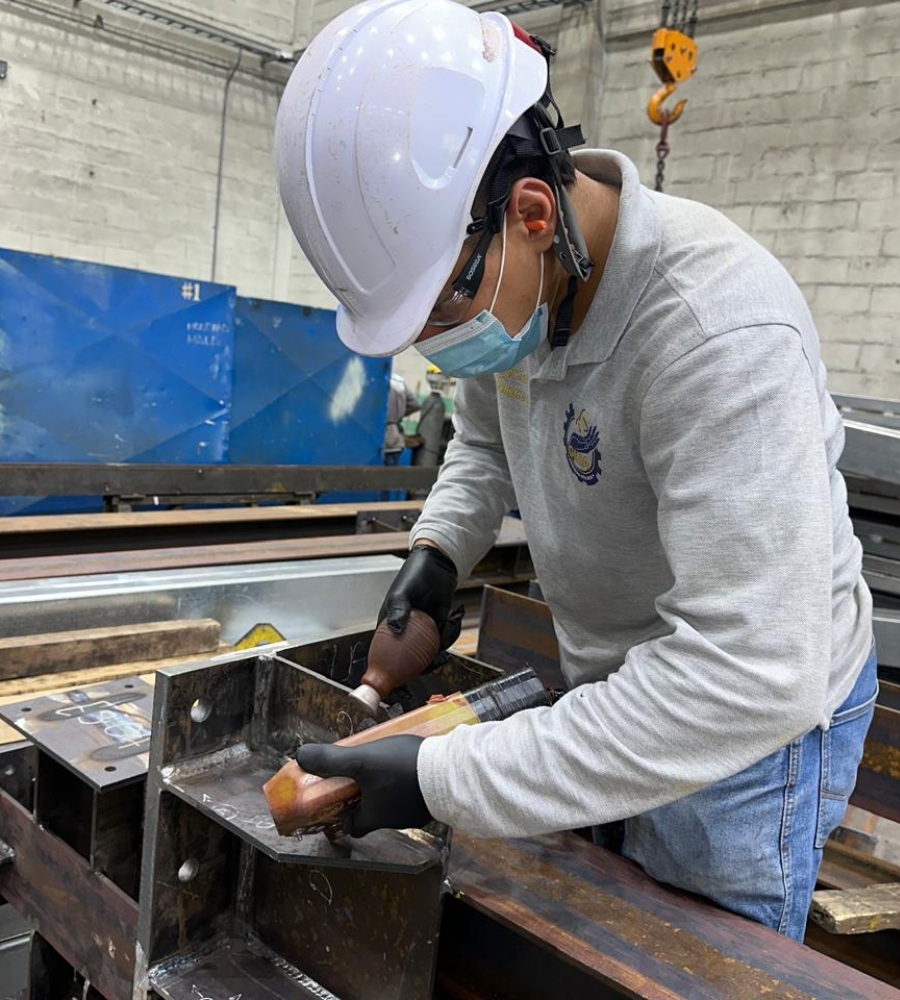 Técnico aplicando producto de ensayo en aerosol sobre una soldadura de estructura metálica
